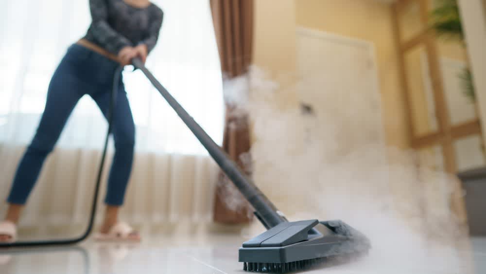 Frau reinigt Boden mit Dampfreiniger