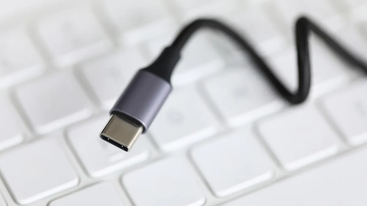 Nahaufnahme eines USB-C-Steckers mit schwarzem Kabel auf einer weißen Tastatur.