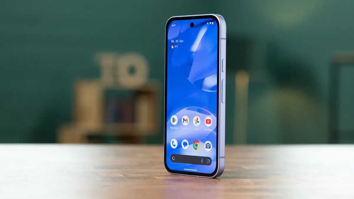 Ein Smartphone mit blauem Bildschirm steht auf einem Holztisch. Auf dem Bildschirm sind App-Symbole zu sehen.
