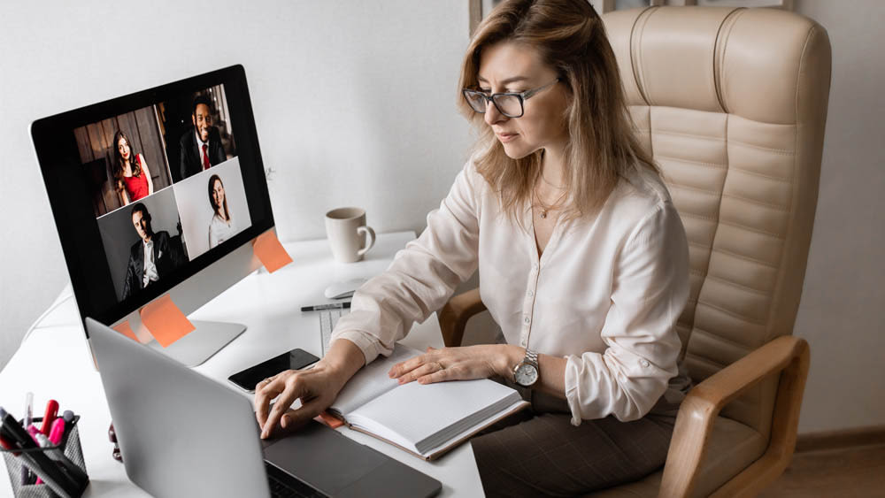 Eine Frau sitzt am Schreibtisch und tippt auf einem Laptop.