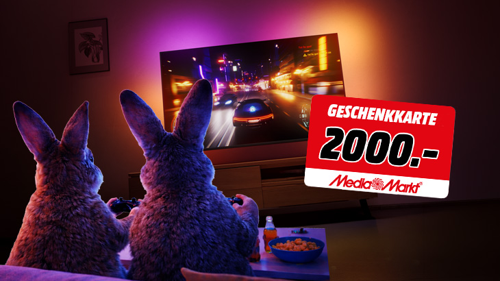 Zwei Hasen zocken vor einem großen Fernseher, daneben eine rote MediaMarkt Geschenkkarte über 2000 Euro.