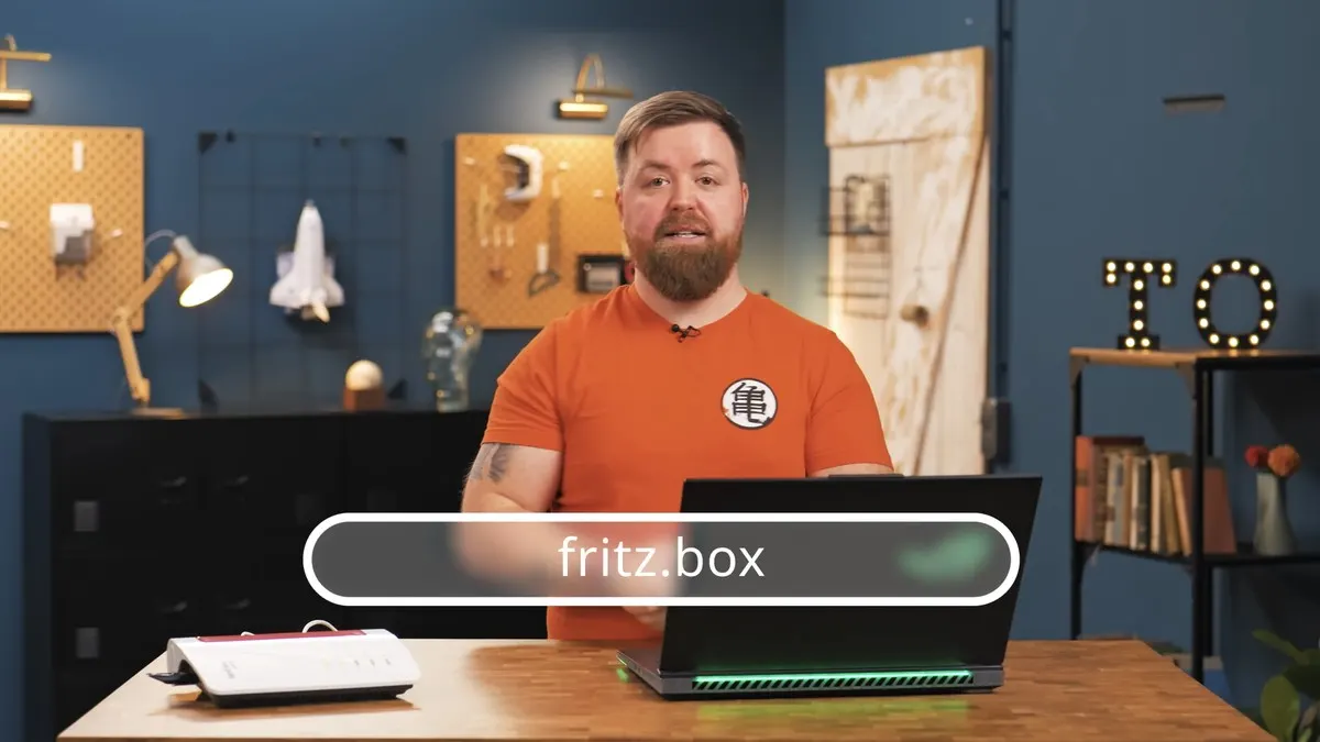 TURN ON Moderator Jens steht vor einem offenen Laptop, daneben steht eine Fritzbox.