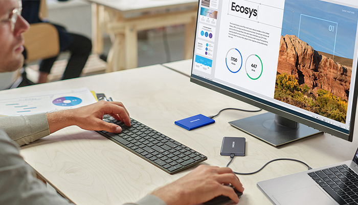 Ein Mann arbeitet an einem Laptop. Auf dem Schreibtisch liegt eine Portable T7, die an den Laptop angeschlossen ist.