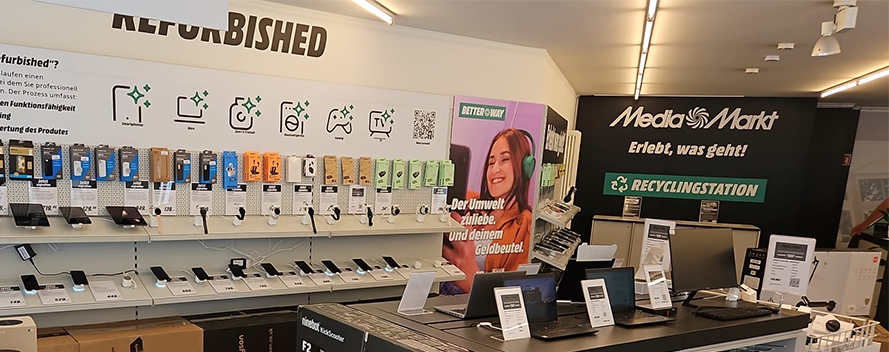 Ein Media Markt-Geschäft zeigt Regale mit Handys, Tablets und Smartwatches. Ein Schild wirbt für wiederaufbereitete Produkte.