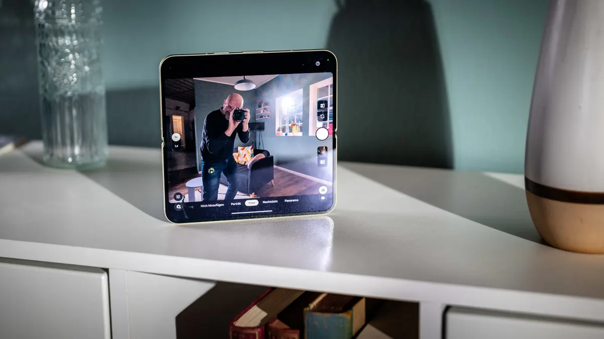 Das Google Pixel 10 Pro Fold steht ausgeklappt im Kameramodus auf einem Sideboard. In der Kameravorschau erkennt man Fotograf Oli.