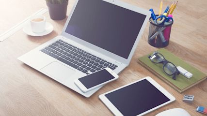 MacBook und iPhone und iPad liegen auf einem Tisch