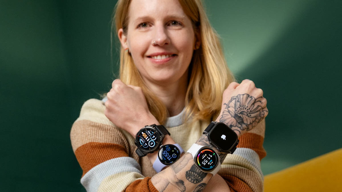 Franzi überkreuzt beide Arme vor dem Oberkörper. Sie trägt an jedem Unterarm zwei Smartwatches. 