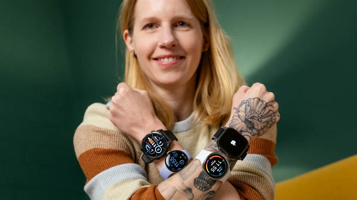 Franzi überkreuzt beide Arme vor dem Oberkörper. Sie trägt an jedem Unterarm zwei Smartwatches. 