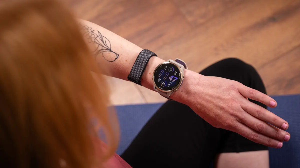 Franzi schaut auf den Garmin Forerunner 970 und das Fitbit Air an ihrem linken Handgelenk.