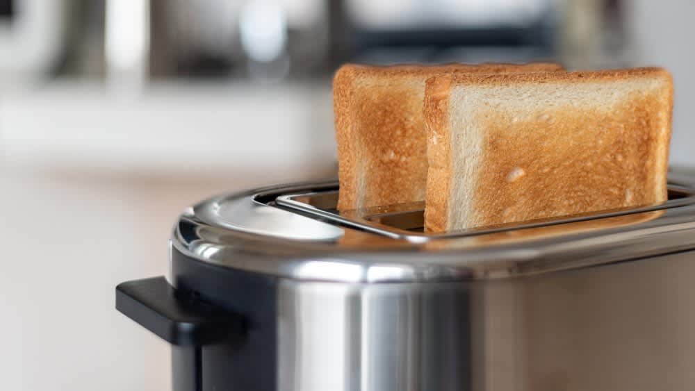 Zwei fertig geröstete Toastscheiben stecken in einem Doppelschlitz-Toaster.