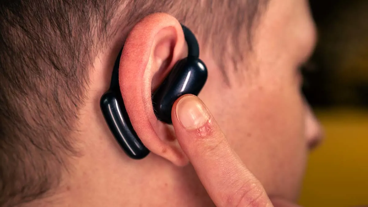 Alex tippt mit dem Finger auf das Touchbedienfeld des rechten Earbuds der Open-Ear-Kopfhörer Soundcore Aerofit 2.