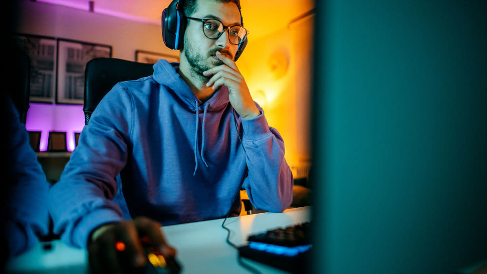 Mann mit Headset bedient Maus am PC.
