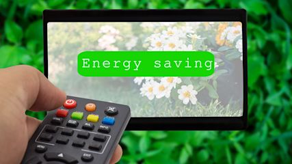 Im Vordergrund ist eine TV-Fernbedienung, die auf einen Bildschirm zeigt. Auf dem TV-Bildschirm stehe: Energy Saving