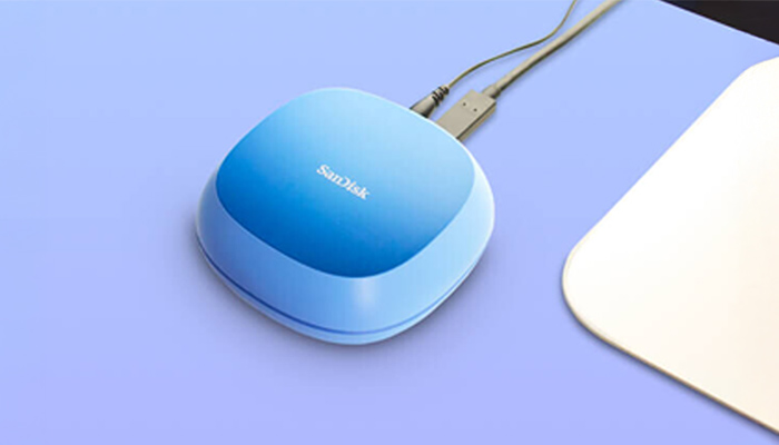 Blaues SanDisk-Gerät mit zwei USB-Kabeln auf blauem Tisch, rechts eine weiße Fläche.