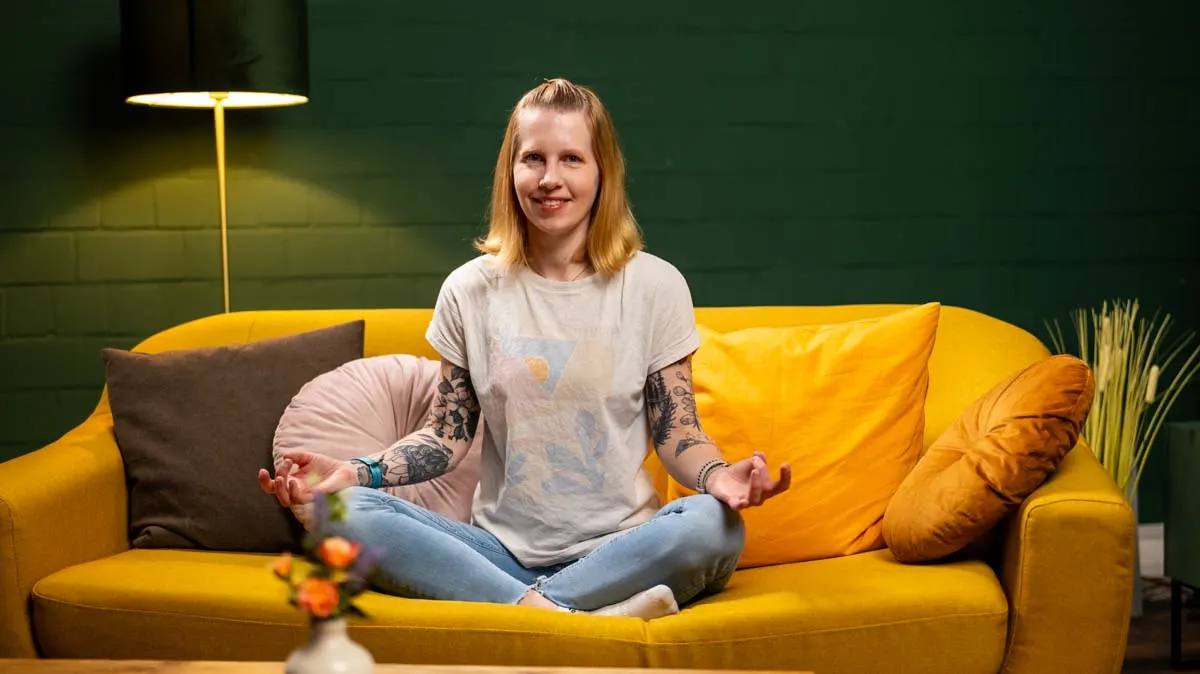 Franzi sitzt in Meditationspose auf dem Sofa.