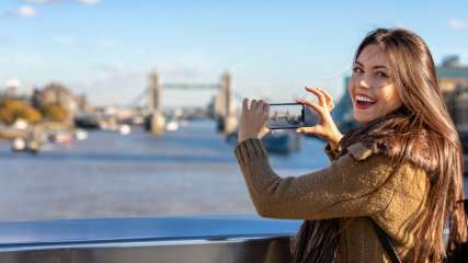 Eine Frau fotografiert in London die Tower Bridge.