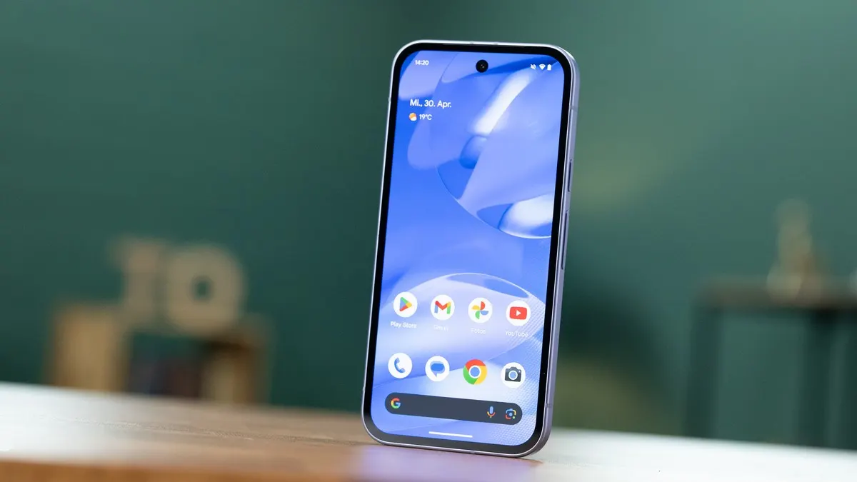 Ein Smartphone mit blauem Hintergrundbild steht auf einem Tisch. Apps sind auf dem Bildschirm zu sehen.