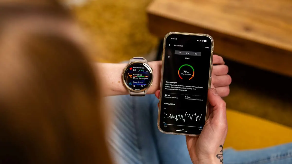 Franzi schaut sich die HRV-Übersicht auf dem Smartphone und der Smartwatch an.