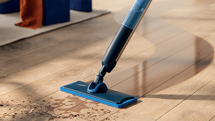 Ein blauer Philips OneUp reinigt einen Holzboden. Vor dem Wischmopp ist Schmutz zu sehen, hinter dem Wischmopp ein sauberer, leicht feuchter Boden.