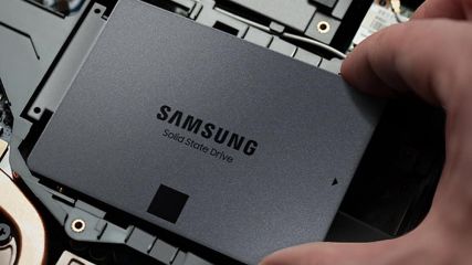 Eine Hand löst eine Samsung-SSD aus der Halterung im Laptop