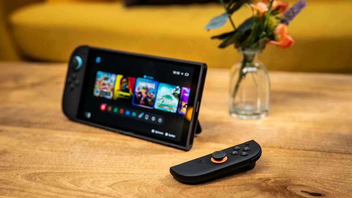 Die Switch 2 steht auf einem Holztisch, im Vordergrund liegt einer der beiden Joy-Cons.