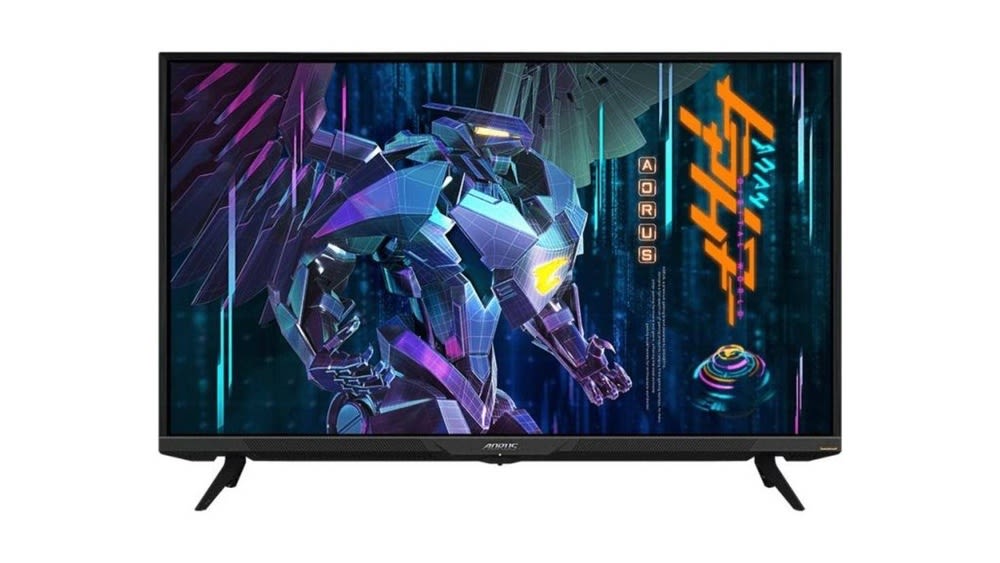 Der Monitor Gigabyte Aorus FV43U steht vor einem weißen Hintergrund und zeigt einen Roboter mit Flügeln auf dem Display.