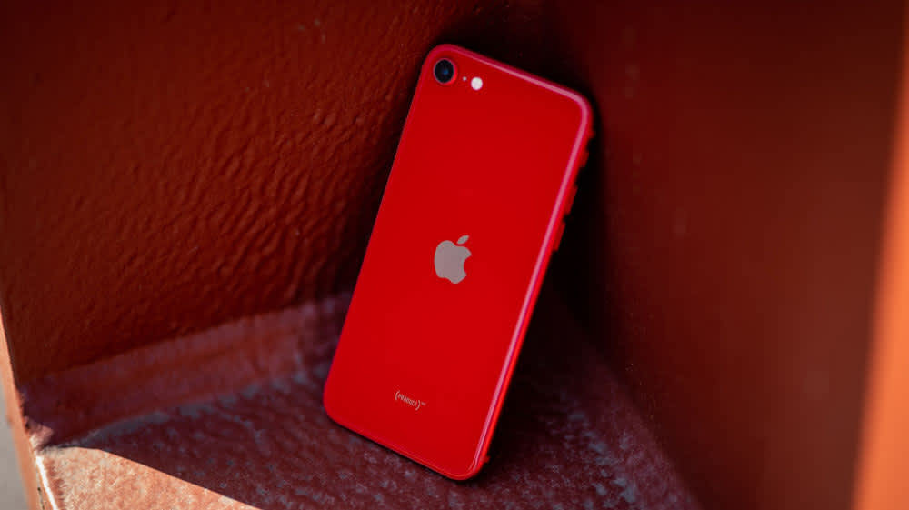 Ein rotes iPhone SE der dritten Generation steht an eine Wand gelehnt.