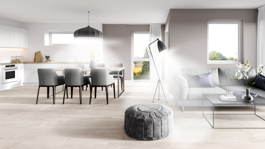 Heller Raum mit Esstisch, Stühlen, Sofa und Hocker. Eine Stehlampe und eine Hängelampe beleuchten den Raum. Fenster zeigen Bäume.