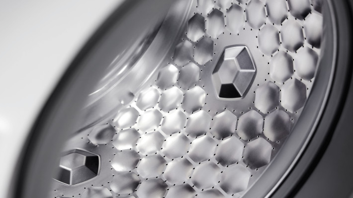 Nahaufnahme einer silberfarbenen Trommel mit einem Muster aus sechseckigen Vertiefungen und drei größeren, sechseckigen Erhebungen.