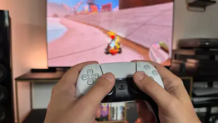 Ein weißer PS5-Controller, der in beiden Händen gehalten wird.