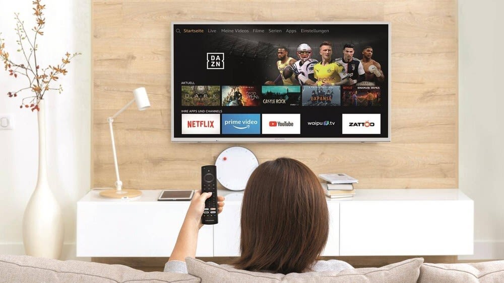 Eine Frau sitzt auf dem Sofa und benutzt einen TV mit Fire OS