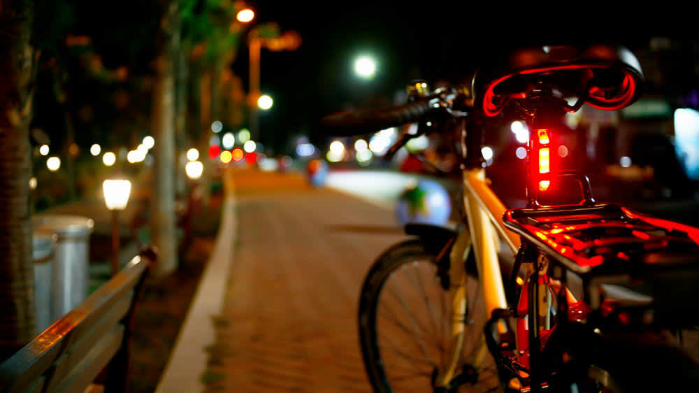 Ein Fahrrad mit rotem Rücklicht steht auf einem Fußweg.