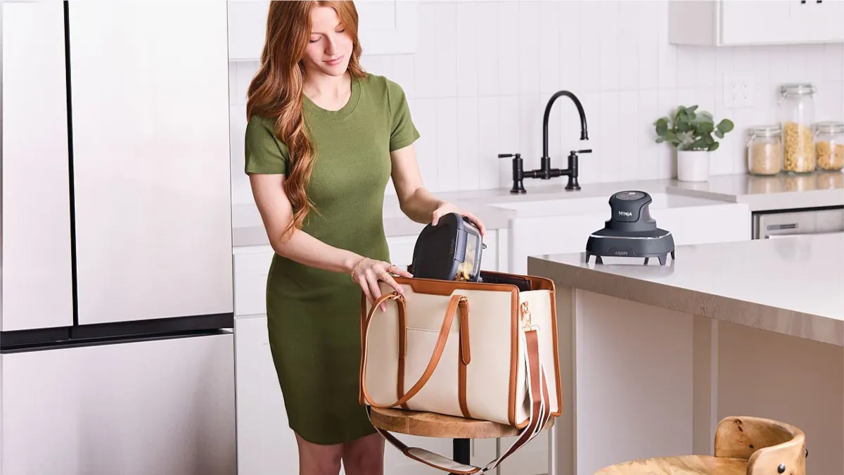 Eine Frau packt die Heißluftfritteuse Ninja Crispi FN101EUGY in eine große Umhängetasche.