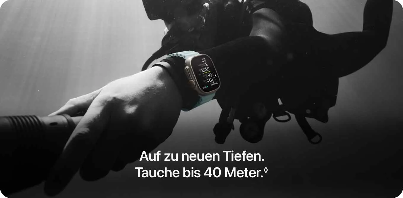 Ein Taucher hält eine Lampe unter Wasser und trägt eine Smartwatch am Handgelenk. Die Uhr zeigt Informationen an.