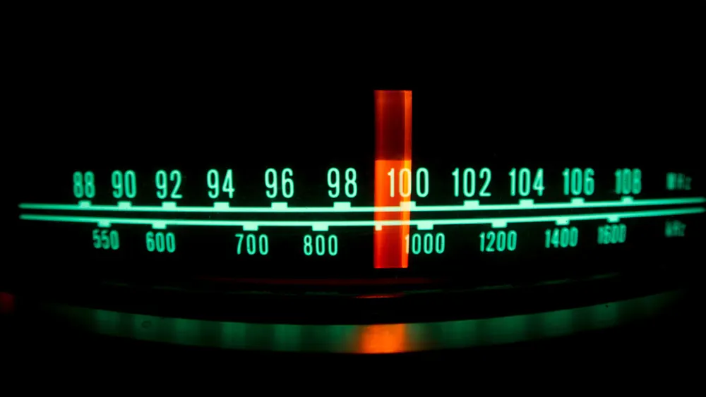 Ein Radiofrequenzband mit grünen Markierungen und Zahlen vor einem schwarzen Hintergrund, ein roter Zeiger steht auf 100.