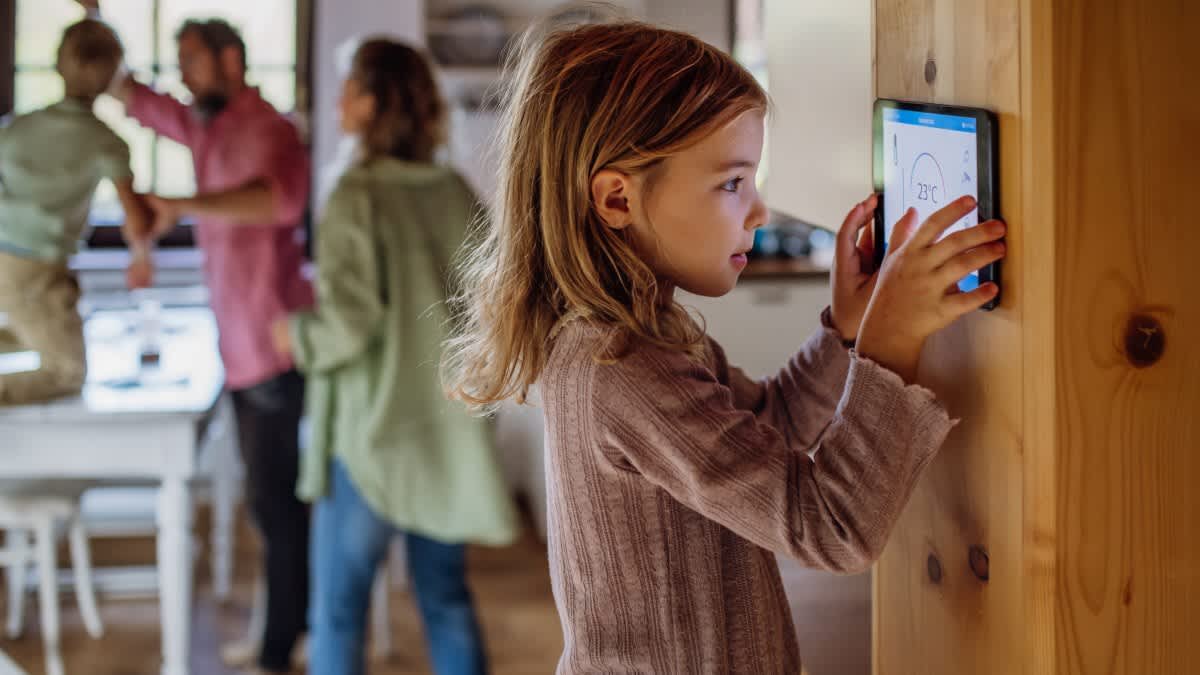 Ein kleines Mädchen bedient ein Smart-Home-Gerät.