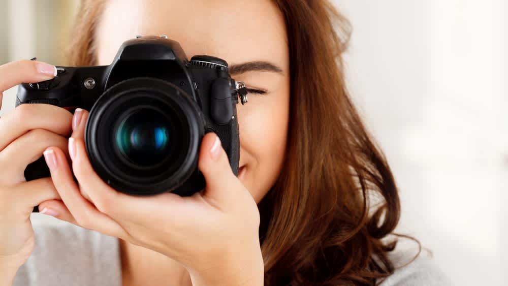 Eine Frau macht ein Foto mit einer digitalen Spiegelreflexkamera.
