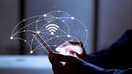 Hände halten Handy darüber steht ein Wlan-Symbol