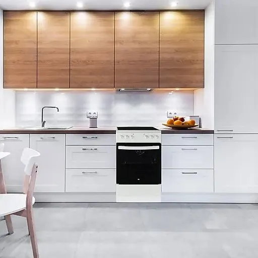 Φωτεινή κουζίνα με λευκά ντουλάπια, ξύλινα ράφια και μια λευκή κουζίνα με μαύρη πόρτα φούρνου. Μπολ με φρούτα στον πάγκο εργασίας.