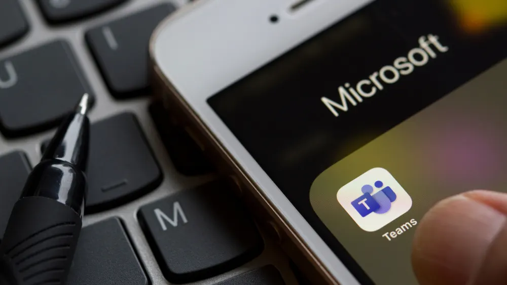 Eine Tastatur mit einem Stift und ein Smartphone, das die Microsoft Teams-App anzeigt.