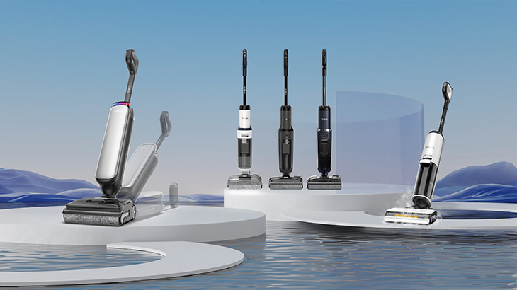 Mehrere Staubsauger in verschiedenen Designs stehen auf einer weißen Plattform vor einem blauen Hintergrund mit Wasser.