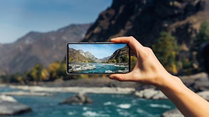 Eine Person knipst mit dem Handy ein Outdoor-Foto in der Natur.