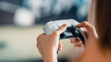 Eine Frau hält einen PlayStation-5-Controller in den Händen.