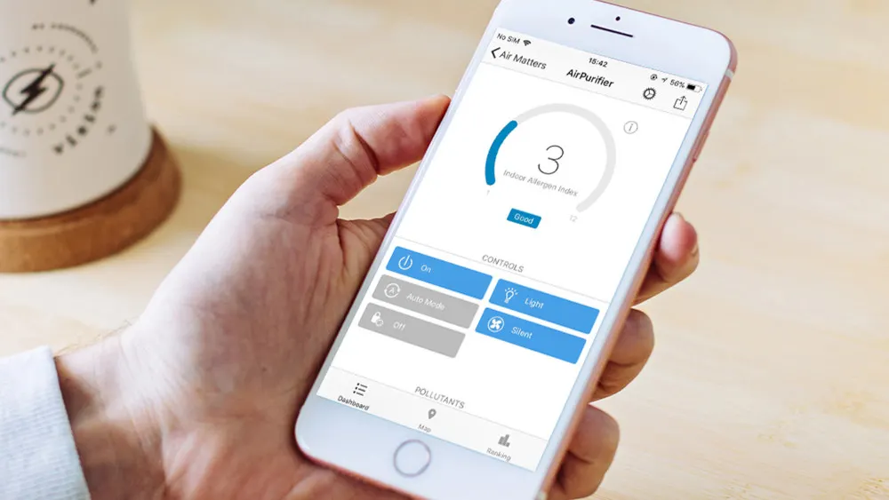 Ein Smartphone zeigt eine App zur Steuerung eines Luftreinigers mit blauen Bedienelementen vor einem hellen Hintergrund.