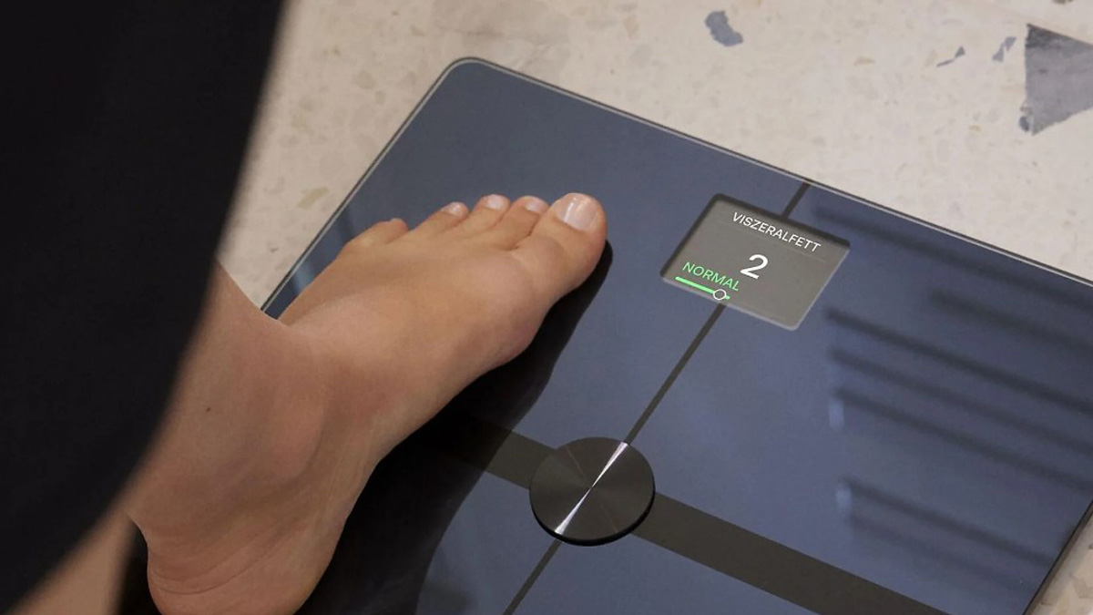 Eine Person steht auf deiner smarten Waage und man sieht die Viszeralfett-Anzeige von 2 mit dem grünen Hinweis "normal".