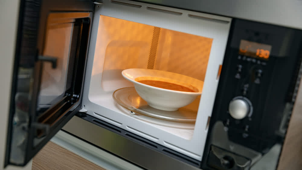 Geöffnete Mikrowelle mit Suppenteller