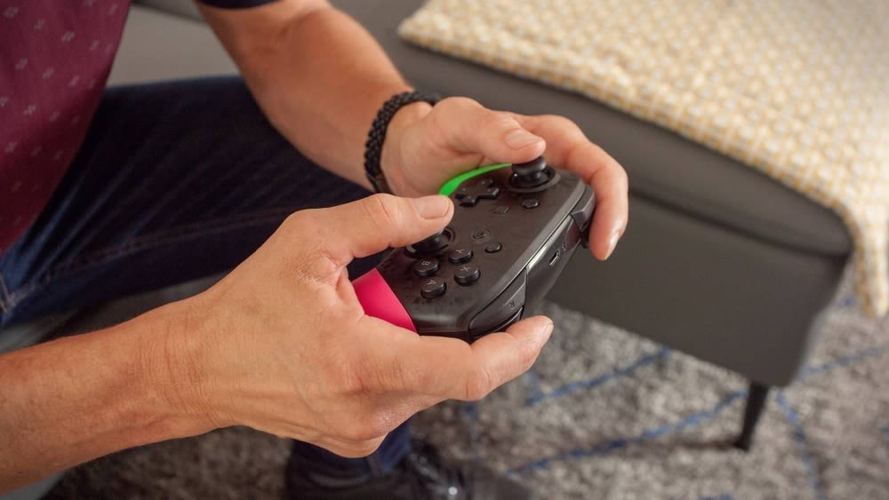 Eine Person hält einen Nintendo Switch Pro Controller in den Händen.