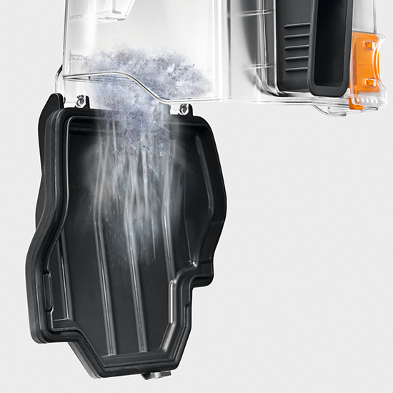 Klarer Behälter mit grauem Inhalt, der in einen schwarzen Behälter entleert wird, vor einem grauen Hintergrund.