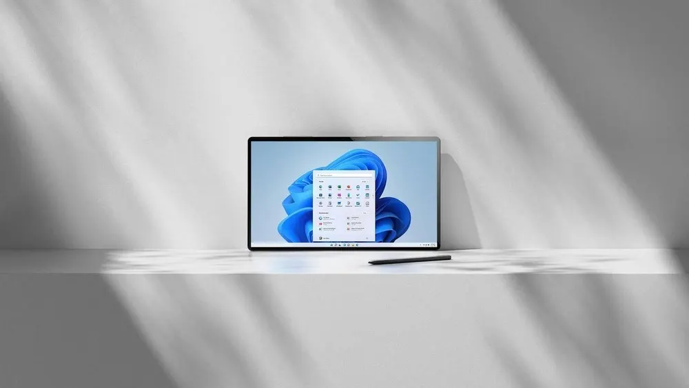 Ein Tablet mit Windows-Oberfläche steht auf einem Tisch, daneben ein Stift. Der Hintergrund ist schlicht weiß mit Schatteneffekten.