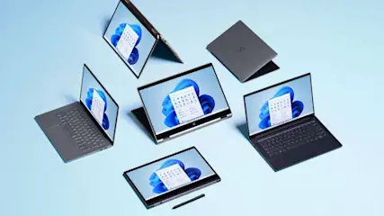 Mehrere Laptops und ein Stift auf hellblauem Grund, einige Laptops sind geöffnet und zeigen einen Kalender.